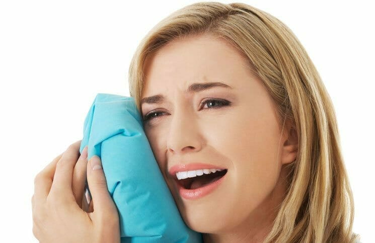 A woman holding a blue towel to her face dental phobia