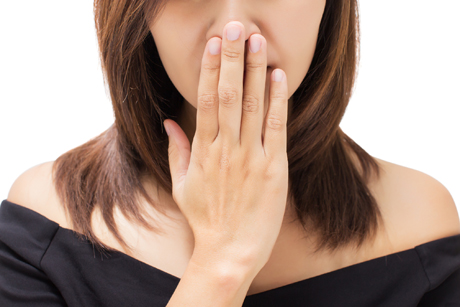 A young woman covering her mouth for Bad breath or Halitosis .article by Pascal Terjanian